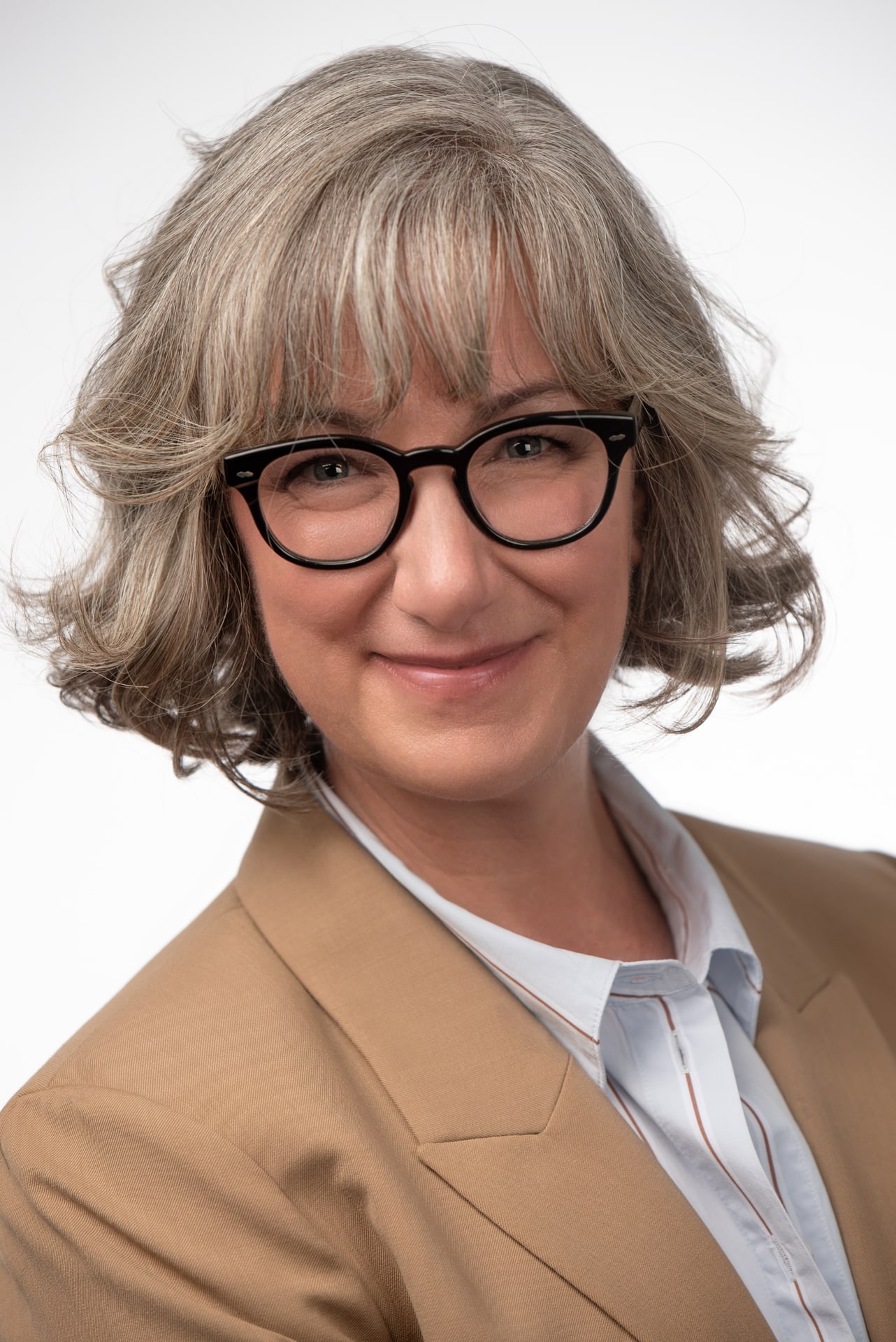 Sussie wearing black glasses and a tan blazer in an executive studio headshot by PhotoTale Studio in Gainesville, Florida.